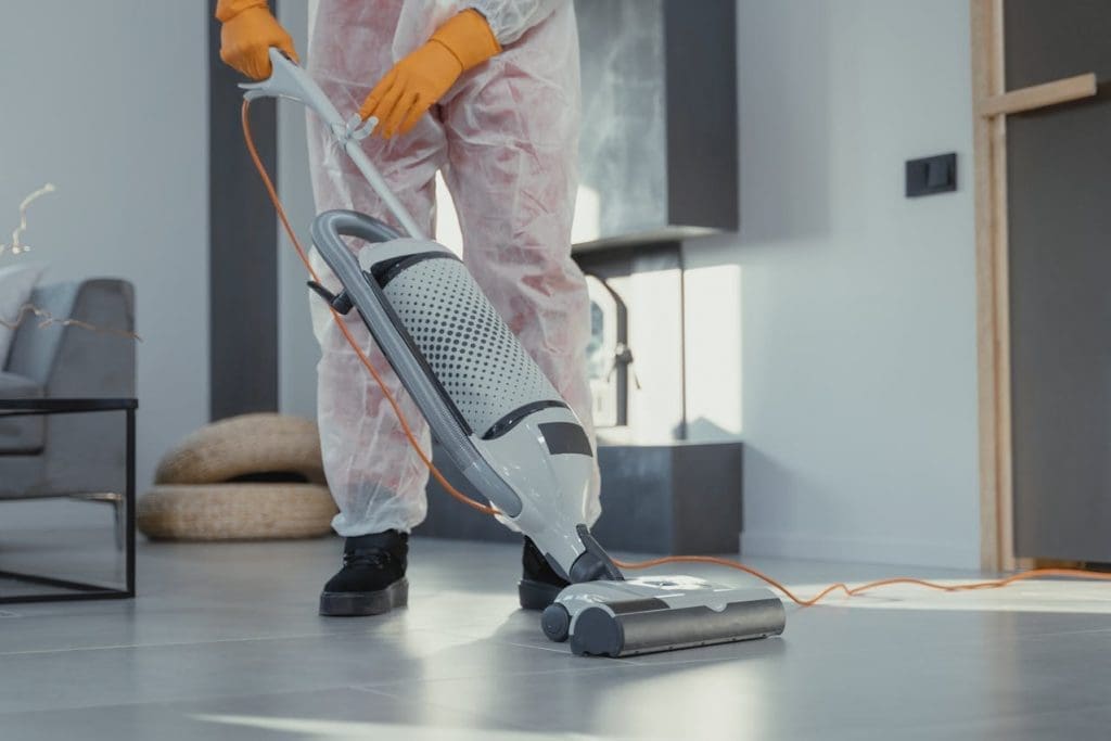 man wearing yellow gloves vacuuming floor