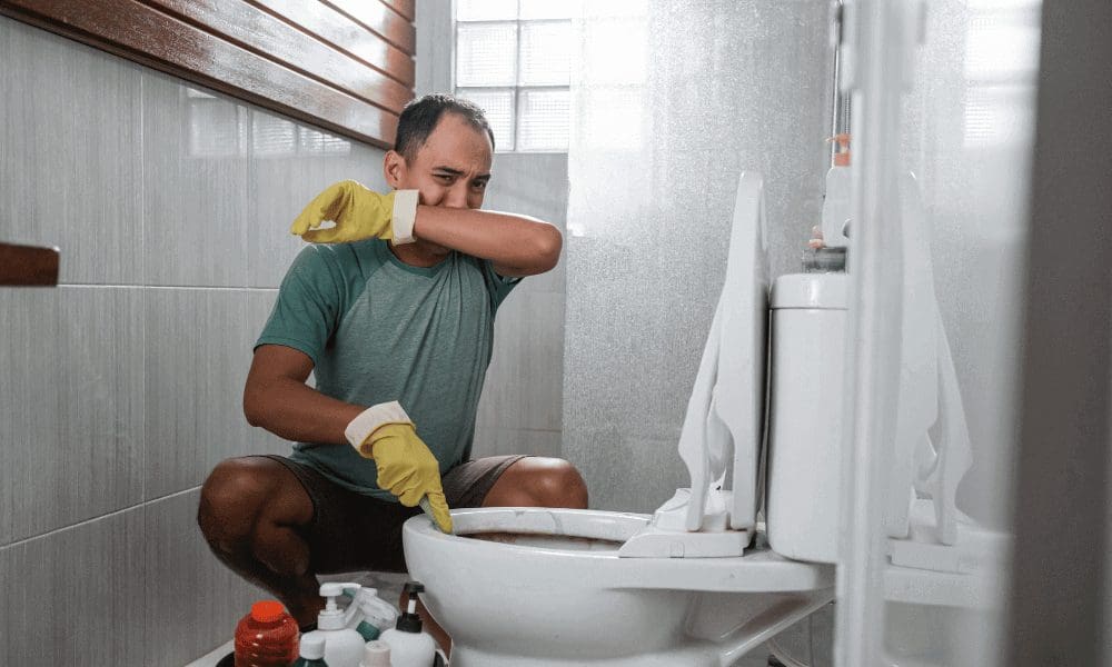 man cleaning the bathroom and covering his nose out of presumably stink